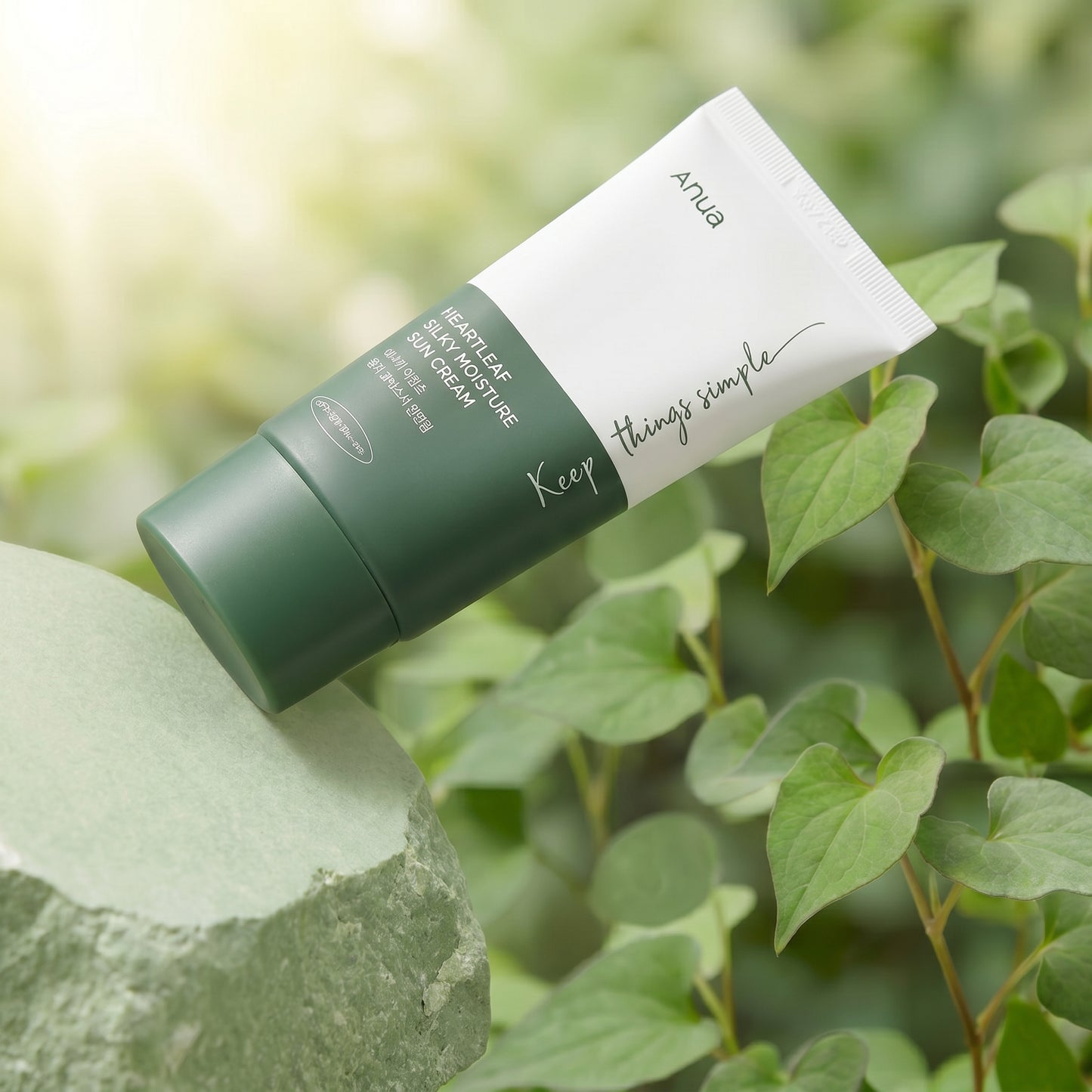 Green and white skincare product tube with 'ANUA' branding against a natural background