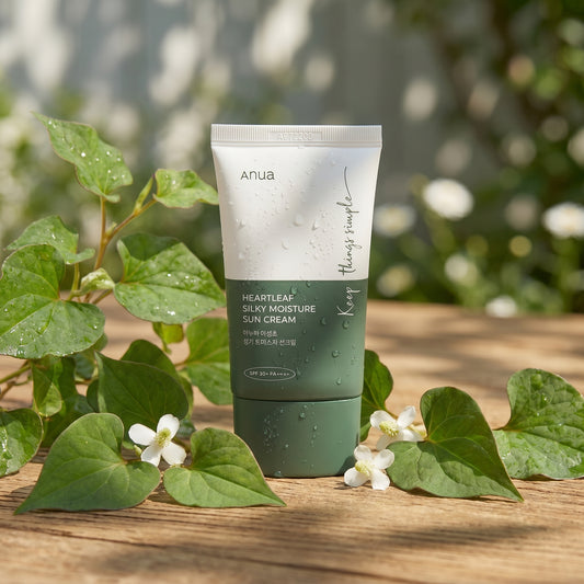 Tube of Anua sunscreen cream on a wooden surface with green leaves and flowers